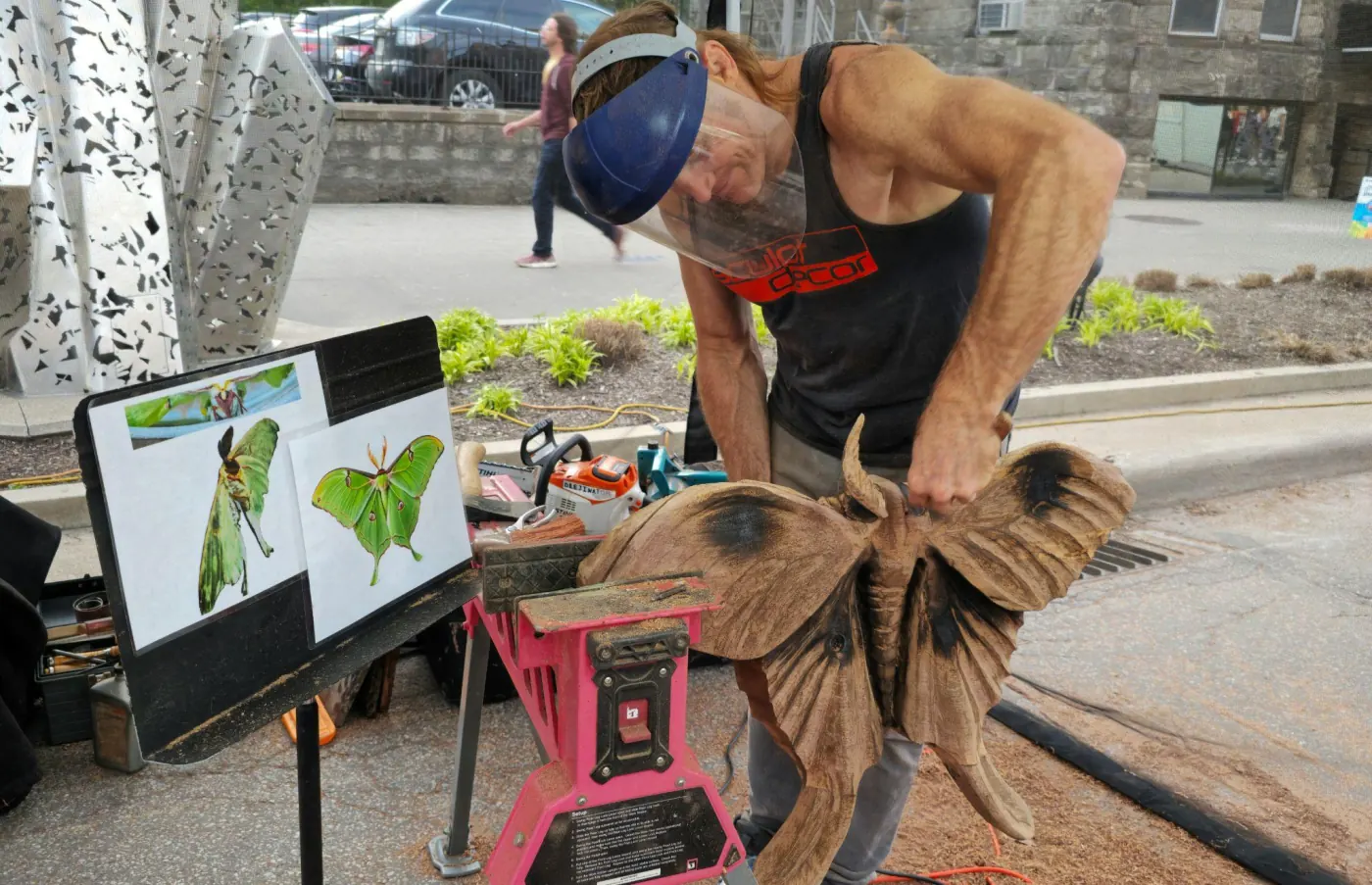 Master sculptor Dustin Weatherby carving a wooden luna moth sculpture during a live sculpting demonstration