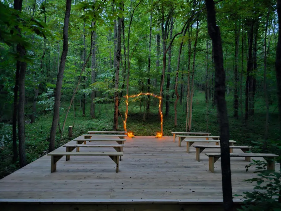 The lantern-lit ceremony arch and benches on the forest platform, set for a micro-wedding