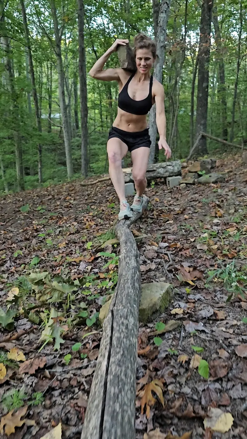 Guest training with a heavy stone at an outdoor conditioning station at Raven's Retreat