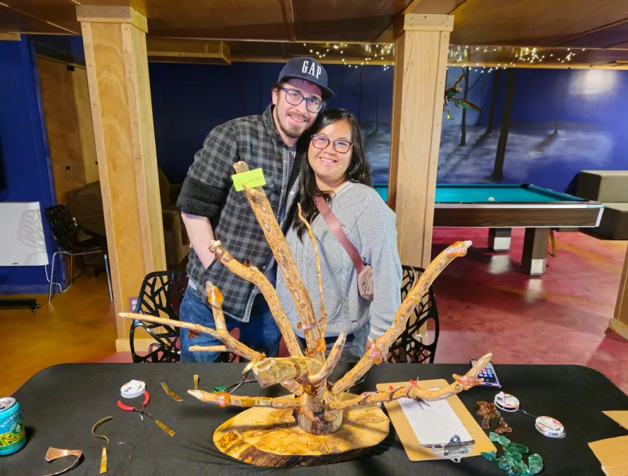 A couple with the driftwood sculpture they built together during a couples retreat