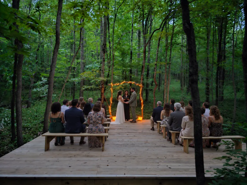 Guests seated on benches for a micro-wedding ceremony on the forest platform at Raven's Retreat
