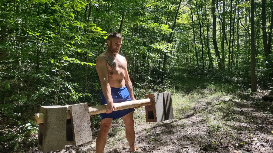 Guest carrying a heavy log between stations on the functional fitness trail at Raven's Retreat