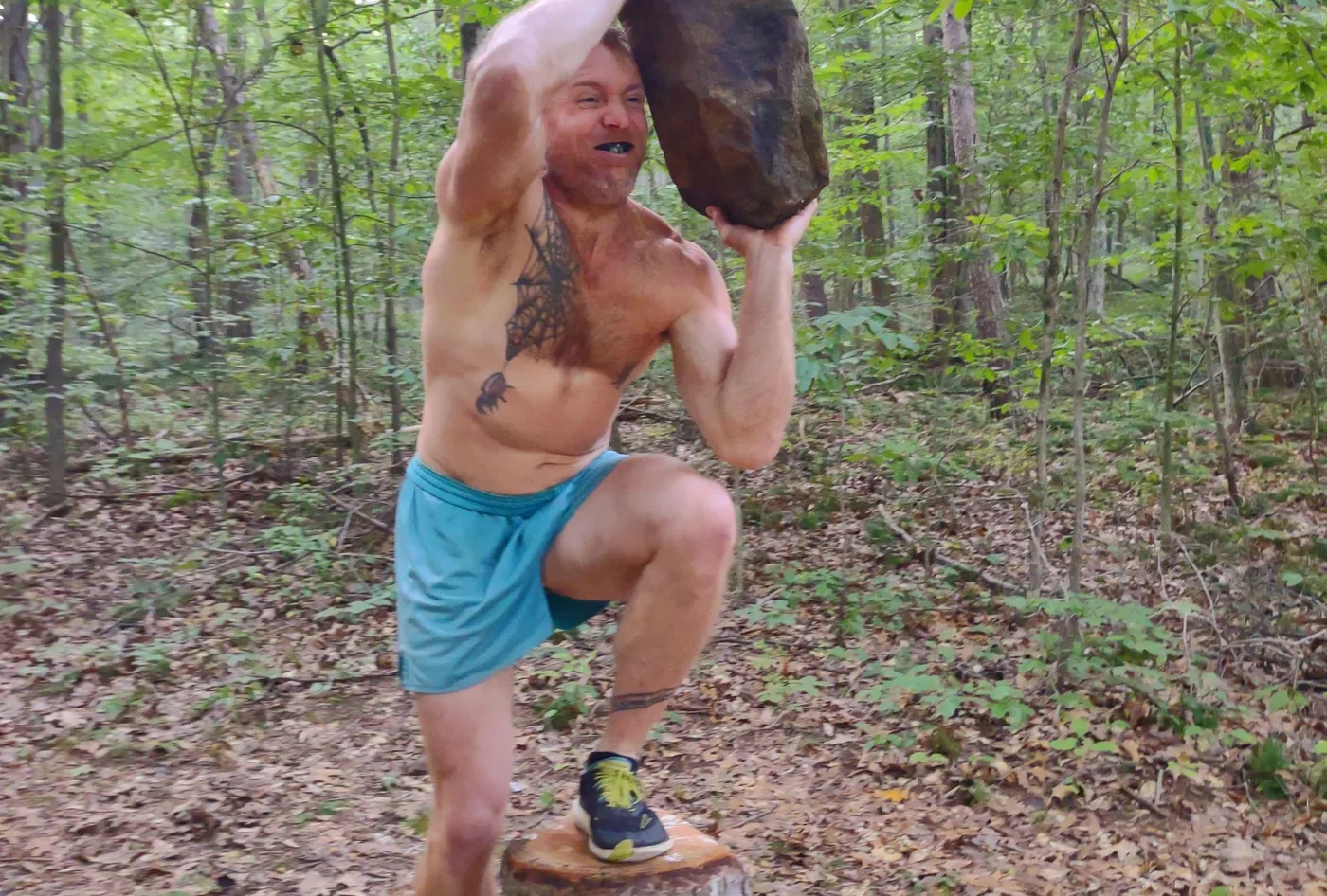 Guest lifting a stone overhead on the wellness trail at Raven’s Retreat Hocking Hills