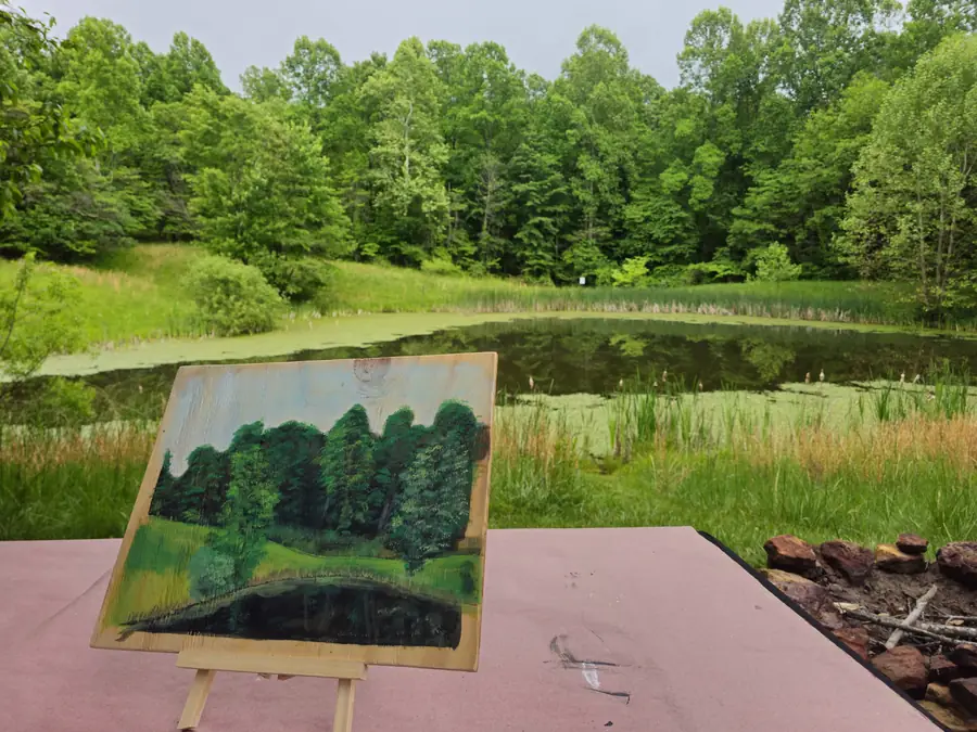 Guest painting at an easel overlooking the pond at Raven’s Retreat Hocking Hills