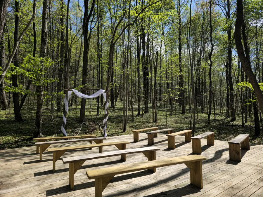 Benches and a ceremony arch set up for a forest wedding on the private preserve