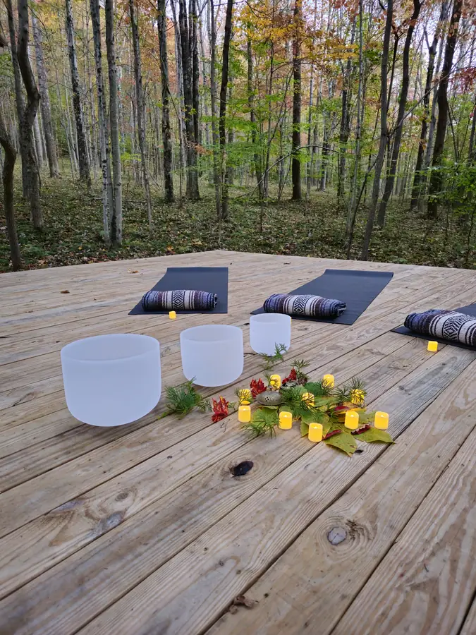 Singing bowls and mats laid out on the forest platform for a group sound bath