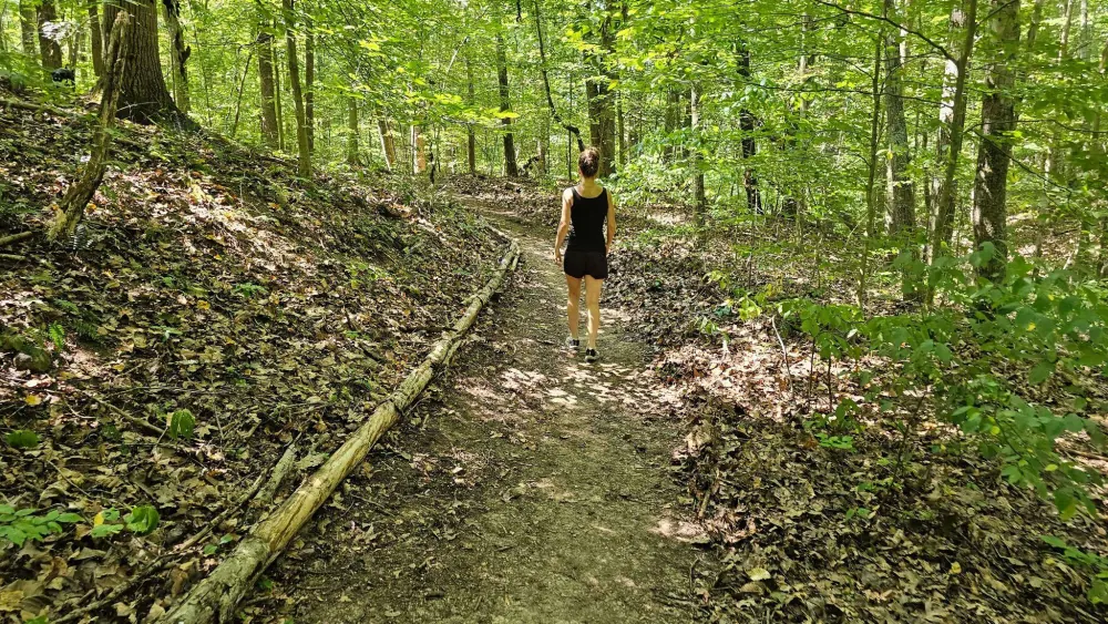 A solo guest walking the private wellness trail through the forest at Raven's Retreat Hocking Hills
