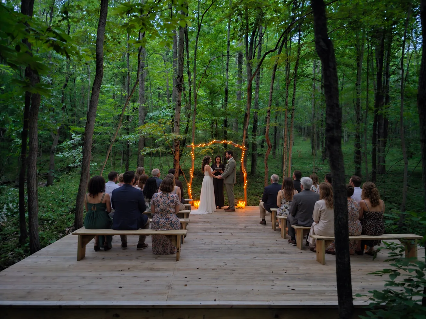 Evening forest wedding ceremony with guests seated on the elevated platform at Raven’s Retreat Hocking Hills